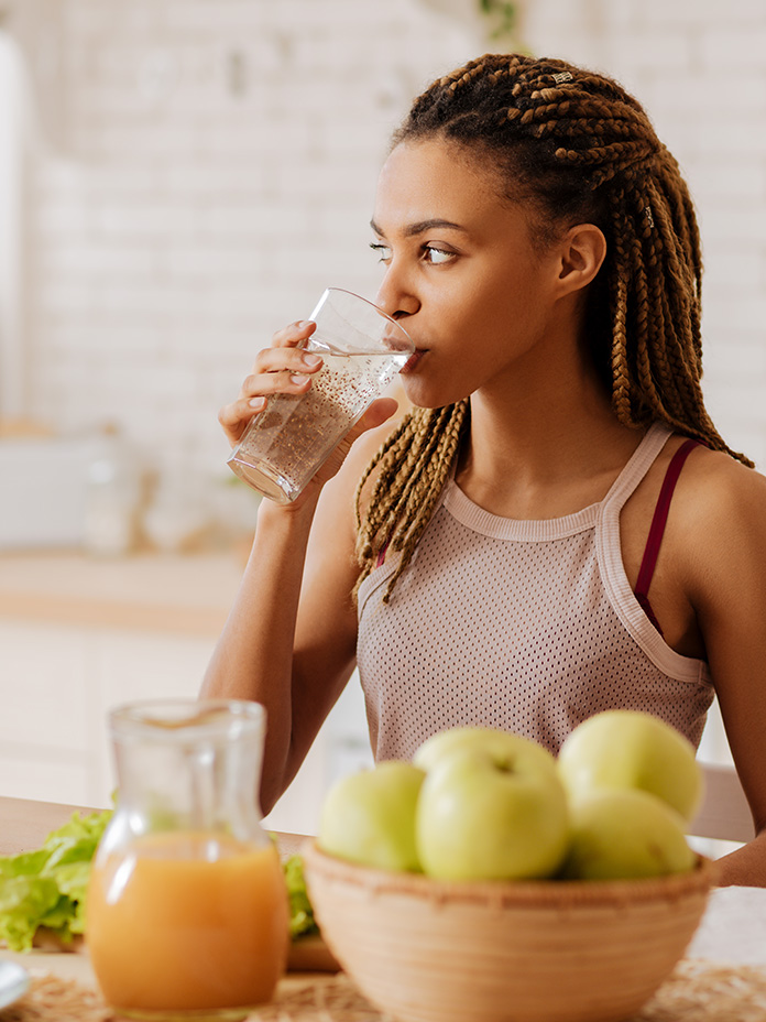 Girl drinking water in front of fruit