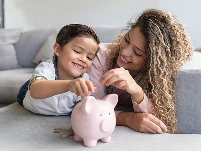 Woman and boy putting coins in piggy bank